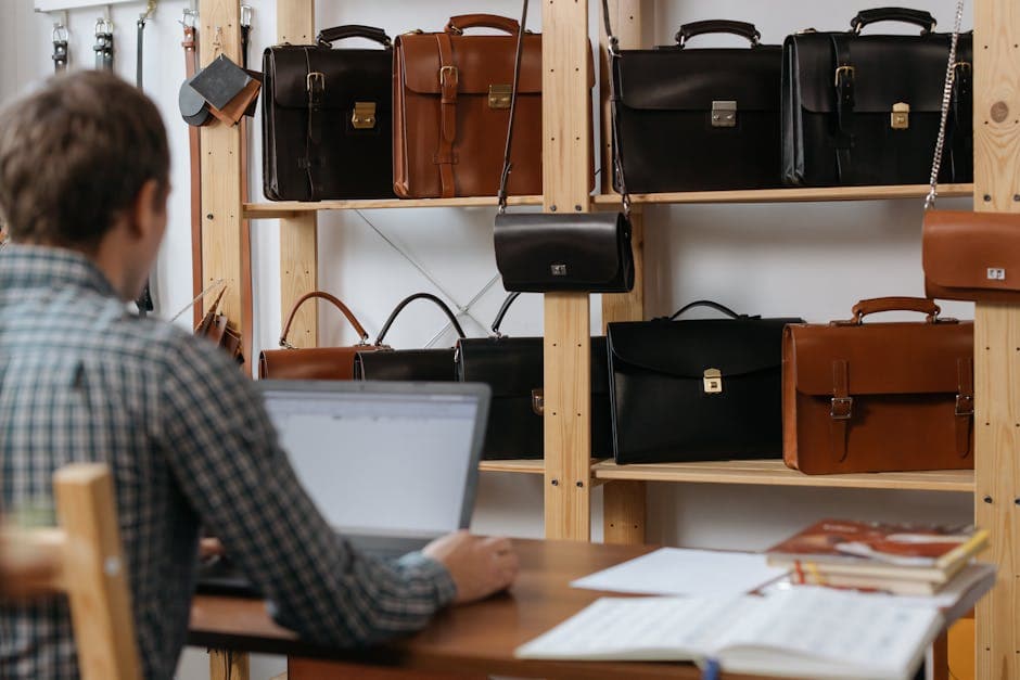Homme à son bureau devant une collection de cartables et sacoches en cuir